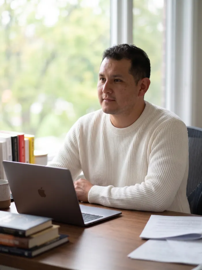 Dennis Alejo working on a laptop by a window